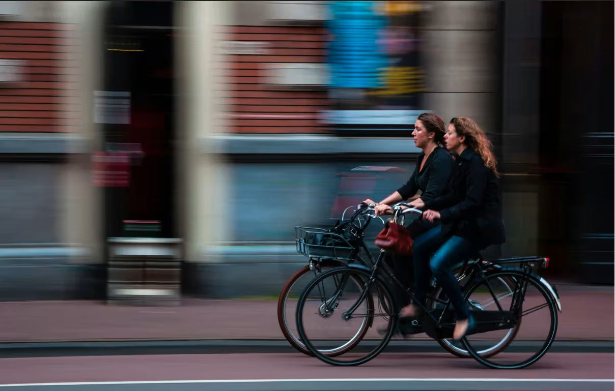 Two women cycling together through a city